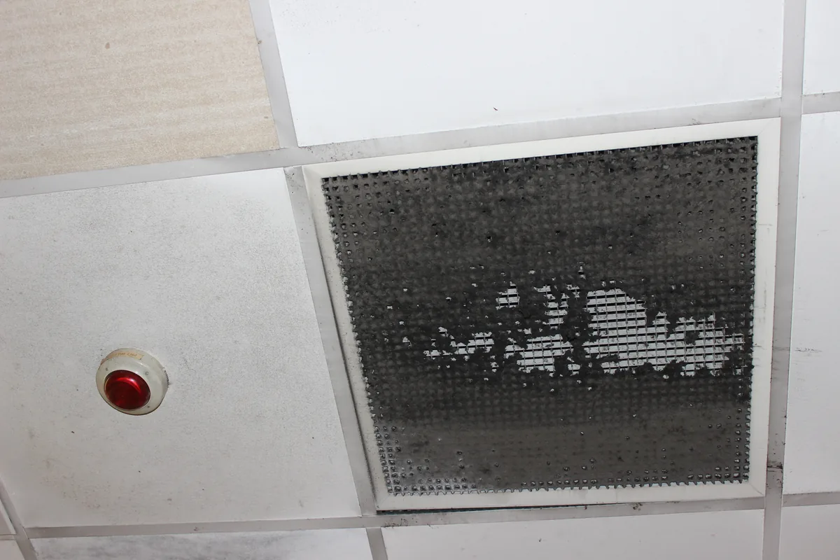 A ceiling grille blackened with grease before the clean
